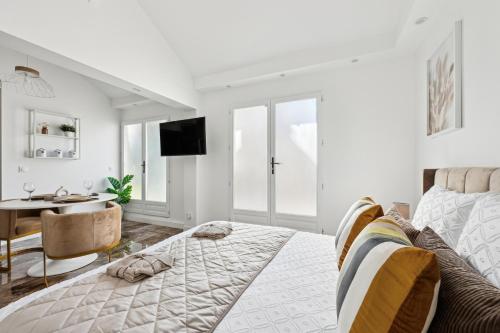 a white bedroom with a bed and a table and a desk at Suite paisible avec jacuzzi in Pontault-Combault