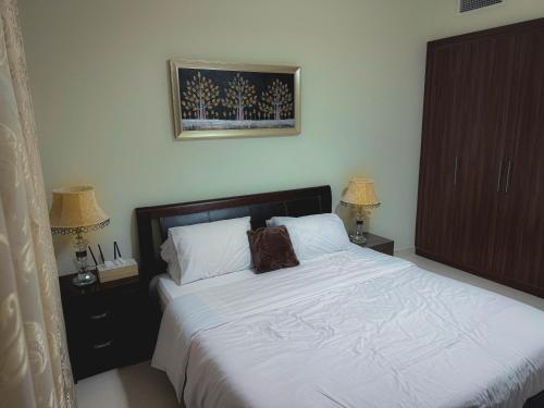 a bedroom with a white bed with two lamps and two cabinets at Modern Space in Prime Location in Dubai