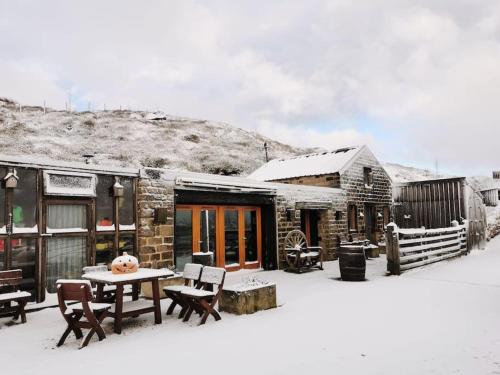a building with a table and chairs in the snow at Cottage incredible views off grid private dog friendly garden cosy in Holmfirth