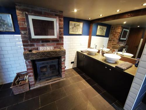 a bathroom with two sinks and a brick fireplace at Cottage incredible views off grid private dog friendly garden cosy in Holmfirth