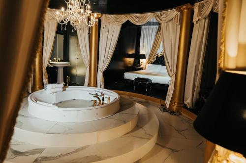a bathroom with a large tub in a room with a bed at Emotional Grand Motel in Fontaneto dʼAgogna