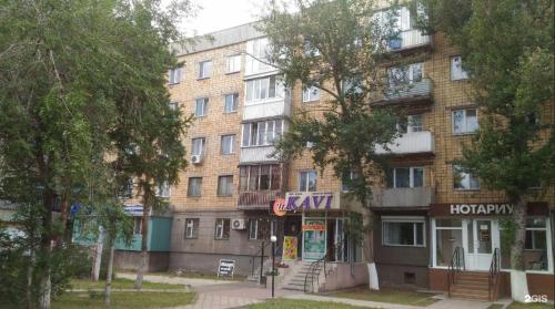 a large brick building with a sign in front of it at City Center Apartment in Karagandy