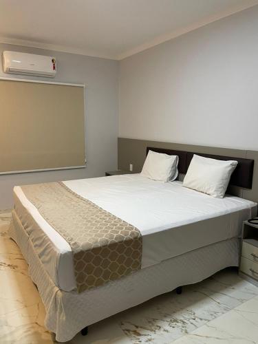 a bedroom with a large bed with a air conditioner at Hotel Uipi in Sorriso