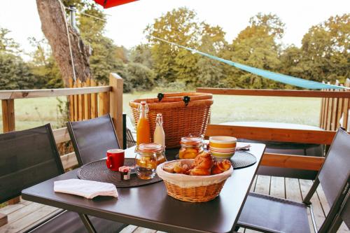 une table avec un panier de nourriture sur une terrasse dans l'établissement Tiny House avec SPA, proche de Bordeaux et de Saint-Emilion, à Castelviel