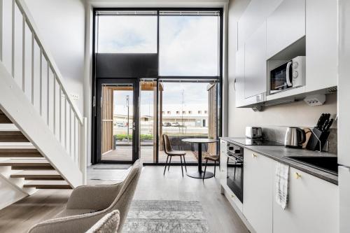 a kitchen with white cabinets and a table with chairs at Kotimaailma - Studio with loft and patio for 2 pax in Turku