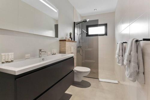 a white bathroom with a sink and a toilet at NEW Luxury 5BR Villa - Casa Graziano by Bocobay in Oranjestad