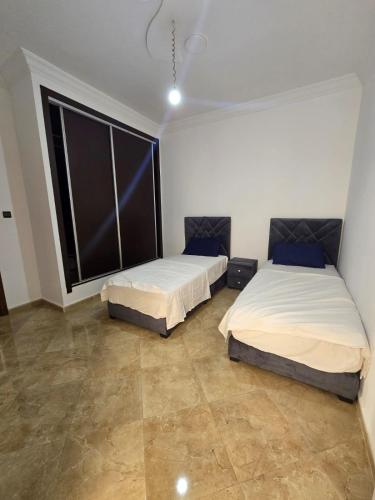 a bedroom with two beds and a large window at Familyconfort oujda in Oujda