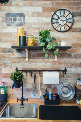 a kitchen with a sink and a clock on a brick wall at The Brick 194, 7 posti letto in Udine