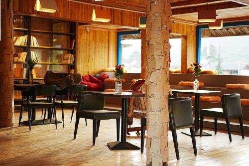 a room with tables and chairs and a tree at Party House in Baisha
