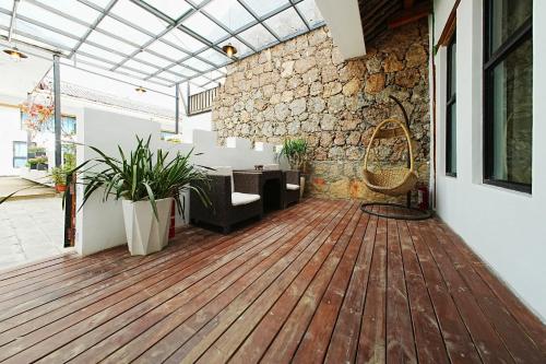 a living room with a wooden floor and a stone wall at Party House in Baisha