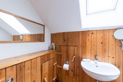 a bathroom with wooden walls and a sink and a mirror at Harmony in Goodwick