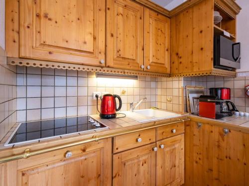 une cuisine avec des placards en bois et un appareil rouge dans l'établissement Charmant appartement 2 chambres à Méribel, proche pistes et commerces - FR-1-355-139, à Méribel