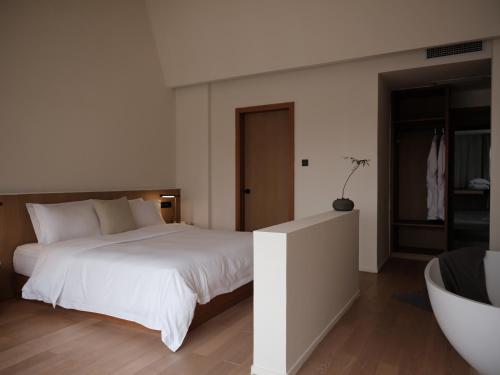 a bedroom with a large white bed and a tub at Guilin Bonjour Boutique Hotel- Free pick up service over 3 nights in Guilin