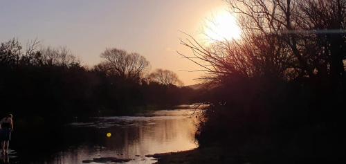 a river with the sun setting in the background at The Loop Farmhouse Mooi River in Mooirivier