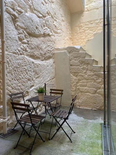 a table and chairs in a room with a stone wall at Oporto Downtown Almada Garden Apartments by LuxiStay in Porto