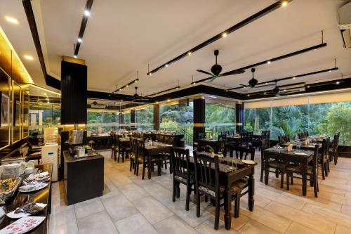 een restaurant met tafels en stoelen en grote ramen bij Casa Rio Resorts Athirappilly in Athirappilly