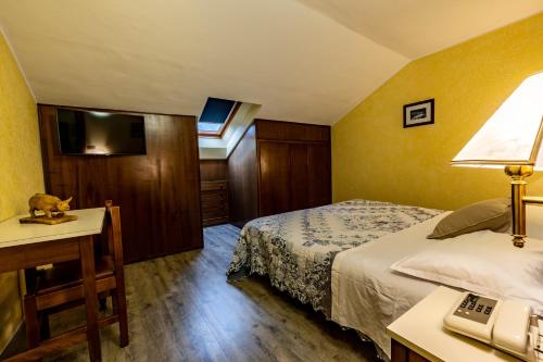 a hotel room with a bed and a desk with a phone at Hotel Beau Sejour Pré-Saint-Didier in Pré-Saint-Didier