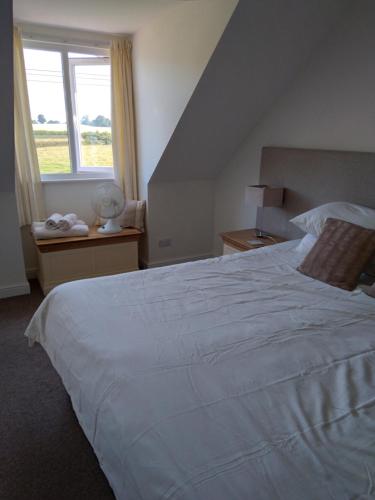 una camera da letto con un grande letto bianco e una finestra di farm cottage with hottub a Ferrensby