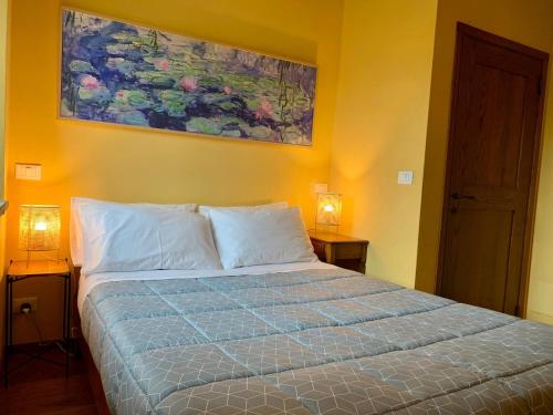 a bedroom with a bed with two lamps and a painting on the wall at Val di Codena - Holiday Home in Vetto