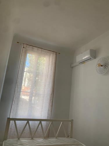 - une fenêtre dans une chambre avec un lit et un rideau dans l'établissement Cœur du Prado À deux, pas des Plage et du stade plein centre, à Marseille