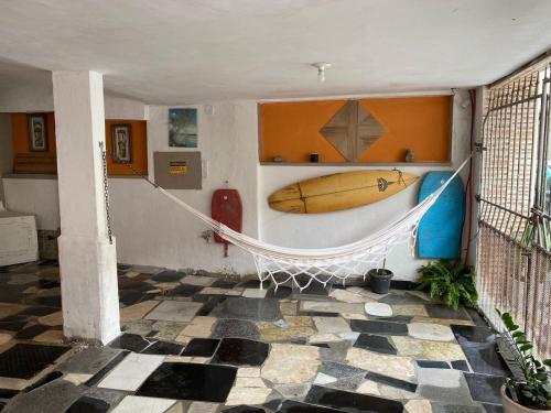 a room with a hammock and a surfboard on a wall at Aconchego do peró in Cabo Frio