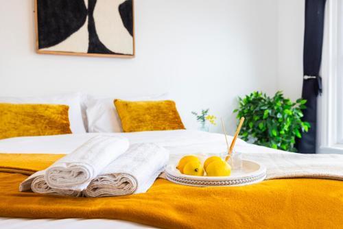 a tray with towels and fruit on a bed at Quick Access to London City, Self Check-in! in London