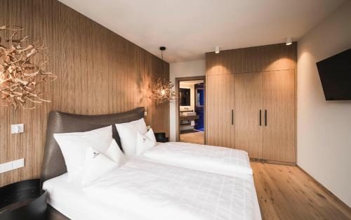 a bedroom with a white bed and a wooden wall at Schenna Resort in Schenna