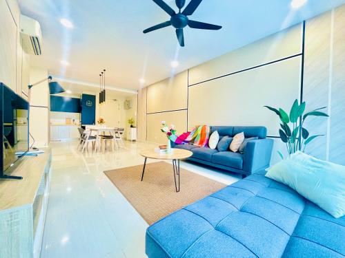 Una sala de estar con un sofá azul y una mesa. en Medini - Signature Of Cosy, en Iskandar Puteri