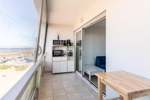 - un salon avec une table et une vue sur la plage dans l'établissement La Lagure, à Courseulles-sur-Mer