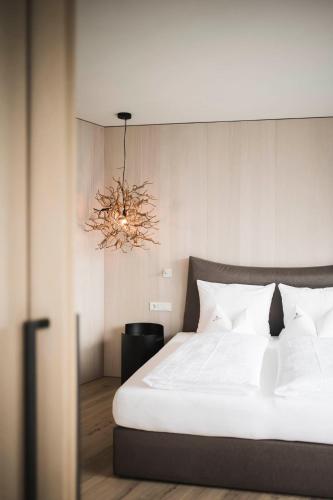 a bedroom with a white bed and a chandelier at Schenna Resort in Schenna