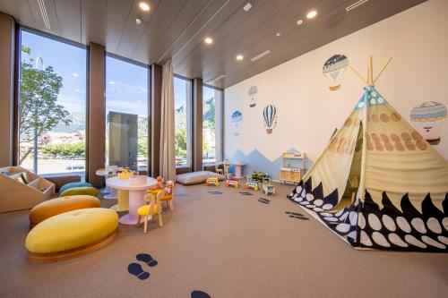 a childrens room with a large room with a large window at SWISSPEAK Resorts Meiringen in Meiringen