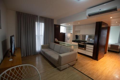 a living room with a couch and a kitchen at H2 Platinum Lourdes in Belo Horizonte
