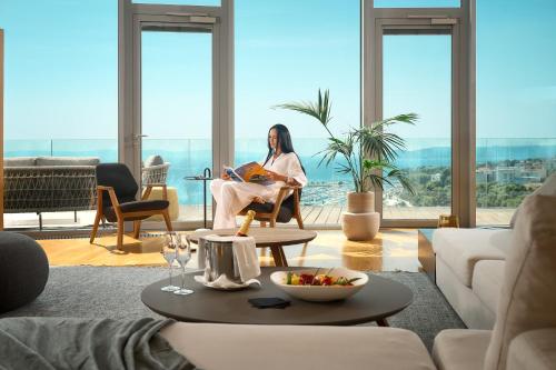 a woman sitting in a chair reading a book in a living room at Radisson Blu Resort & Spa in Split