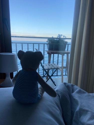 a teddy bear sitting on a bed looking out a window at Terrazza Roberto in Cefalù