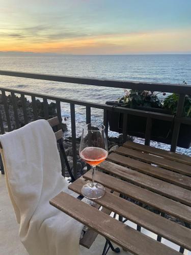 a glass of wine sitting on a bench overlooking the ocean at Terrazza Roberto in Cefalù