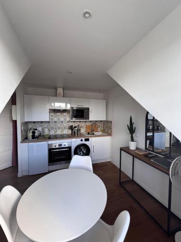 - une cuisine avec une table blanche et des chaises blanches dans l'établissement Charmant Studio Centre ville, à Caen