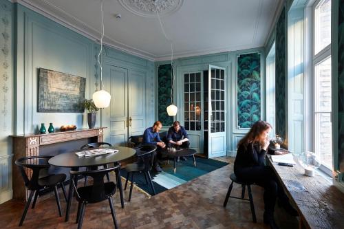 a group of people sitting around a table in a room at Hotel Monsieur Ernest in Bruges