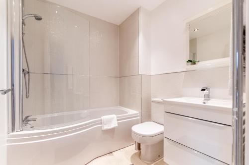 a white bathroom with a tub and a toilet and a sink at Black Brick Stays, Great Location, Free Parking, Fast Wi-Fi, Families & Contractors Welcome in Peterborough