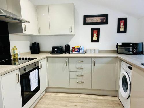 a kitchen with white cabinets and a washer and dryer at Spacious Home with On-Street Parking in Cardiff