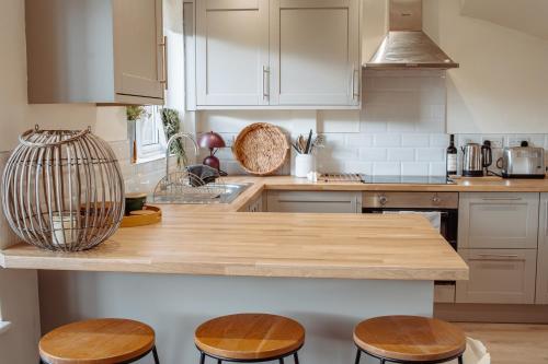 a kitchen with a wooden counter top and stools at Modern Bright Spacious Home in Moortown