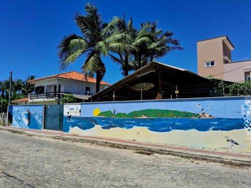 a wall with a mural of a beach and a palm tree at Floripa Surf Hostel in Florianópolis