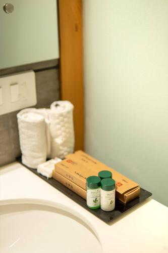 a bathroom counter with toiletries on a shelf next to a sink at Mastiff Select Mandavya Dharamkot, McLeodganj in Dharamshala