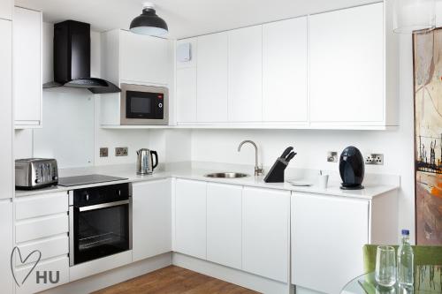 une cuisine blanche avec des armoires et des appareils blancs dans l'établissement Boutique 1 Bdrm Duplex Suite on Marina 305, à Hull
