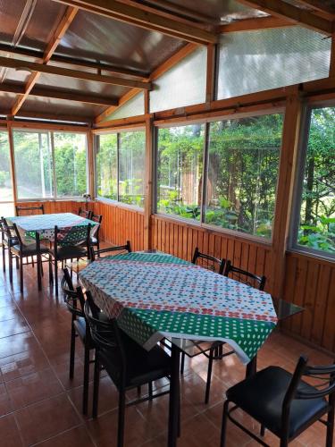 a screened in porch with tables and chairs and windows at Hospedaje Casa Betalpu in Culenar
