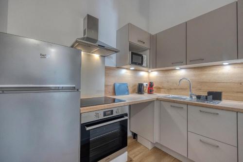 une cuisine avec des armoires blanches et un réfrigérateur en acier inoxydable dans l'établissement #HG Beautiful T2 renovated in the hyper center facing train station, à Grenoble