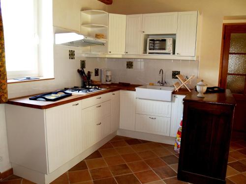 une cuisine avec des armoires blanches et un comptoir dans l'établissement Le Petit Moulin Côté Cour, à Nailly