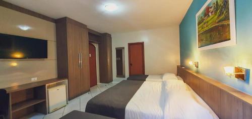 a bedroom with a bed and a flat screen tv at Hotel das Américas in Balneário Camboriú