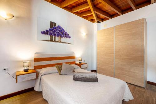 una camera da letto con un grande letto bianco con fiori viola sul muro di Casa Frente al Mar La Ponderosa a Caleta de Interián