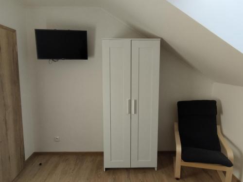 einen weißen Schrank und einen Stuhl in einem Zimmer in der Unterkunft Ubytování v Žimrovicích in Hradec nad Moravicí