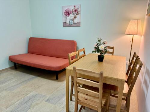 a living room with a table and a red couch at Sun Beach Apartment in Anavissos